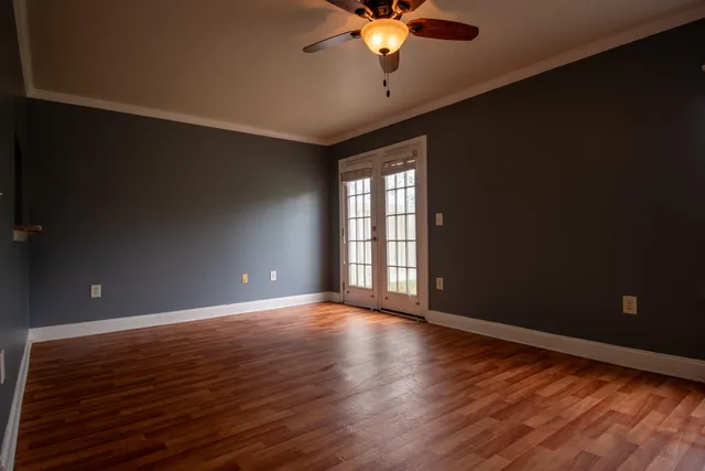 a view of an empty room with a window and wooden floor