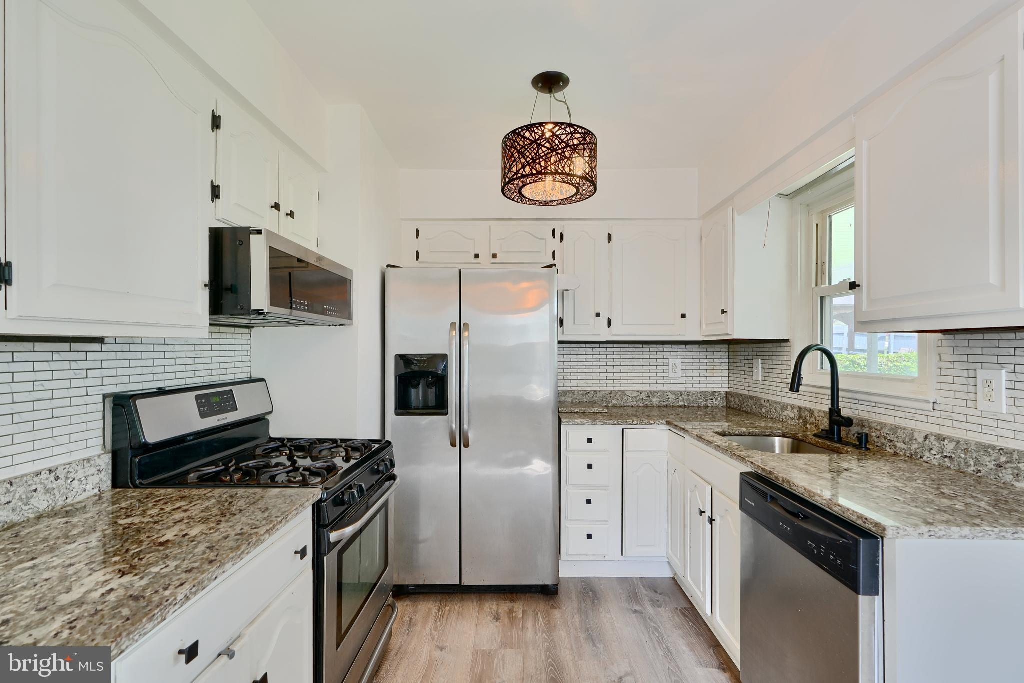 8203 Oakleigh Road Baltimore, MD 21234 - Photo 16 of 56 a kitchen with stainless steel appliances granite countertop a stove a sink dishwasher and a refrigerator with wooden floor