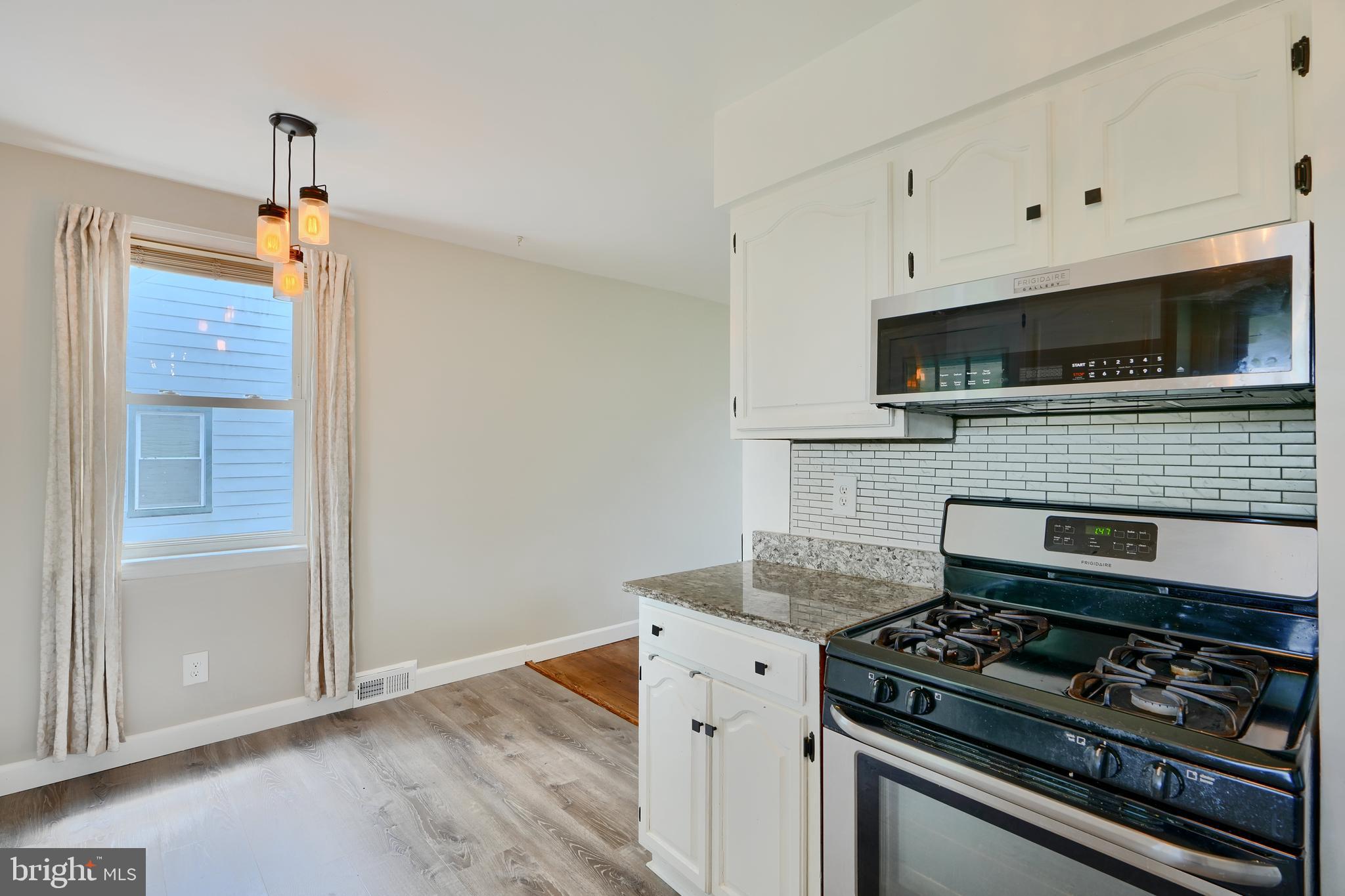 8203 Oakleigh Road Baltimore, MD 21234 - Photo 19 of 56 a kitchen with granite countertop cabinets stainless steel appliances and wooden floor