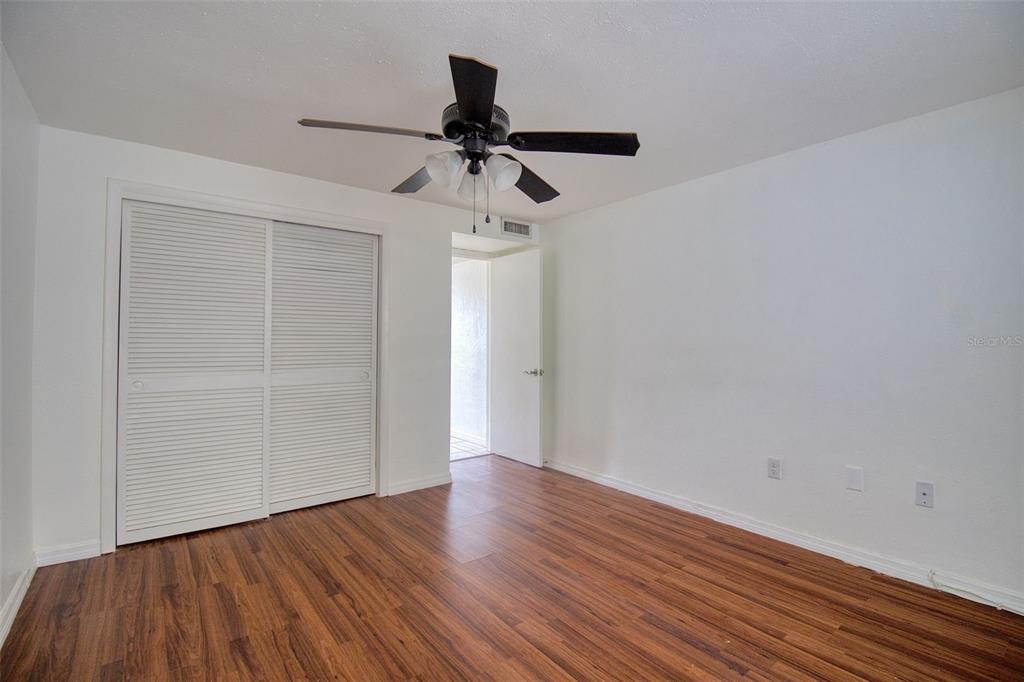 4242 Redcliff Place, Unit C New Port Richey, FL 34652 - Photo 13 of 15 a view of an empty room with wooden floor and a ceiling fan