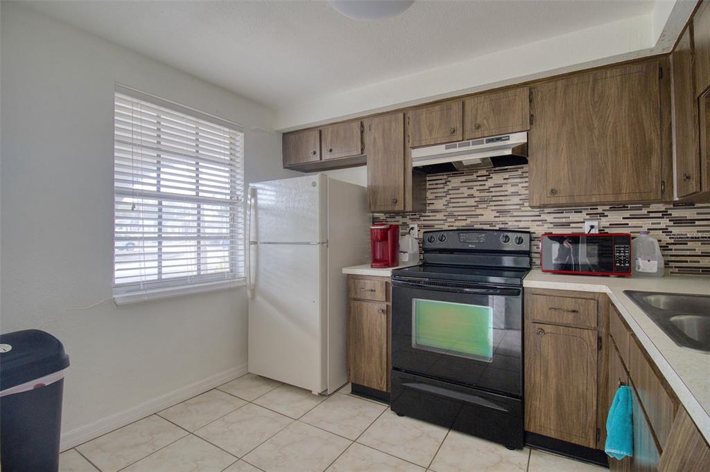 4242 Redcliff Place, Unit C New Port Richey, FL 34652 - Photo 3 of 15 a kitchen with a stove a refrigerator and cabinets
