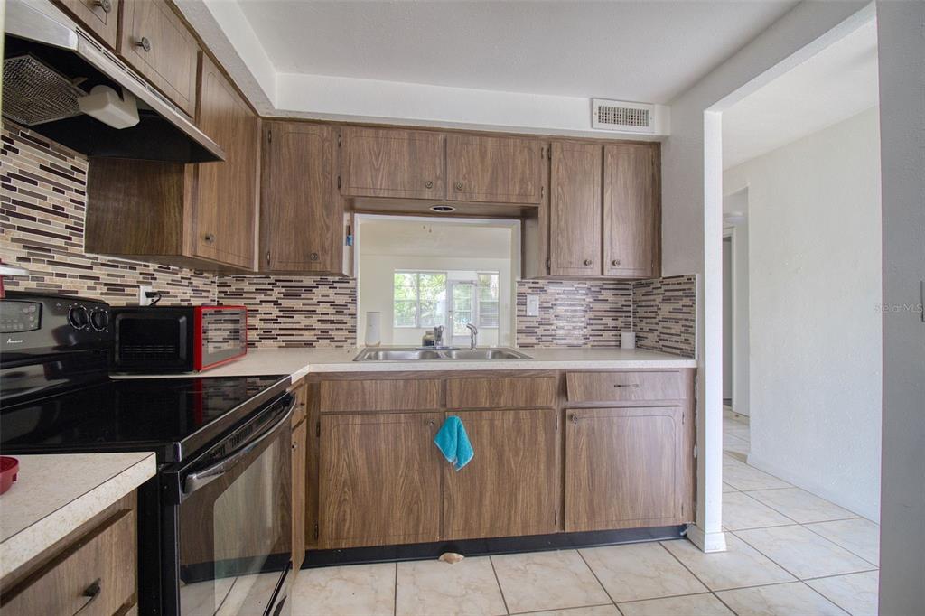 4242 Redcliff Place, Unit C New Port Richey, FL 34652 - Photo 4 of 15 a kitchen with stainless steel appliances granite countertop a sink stove and cabinets