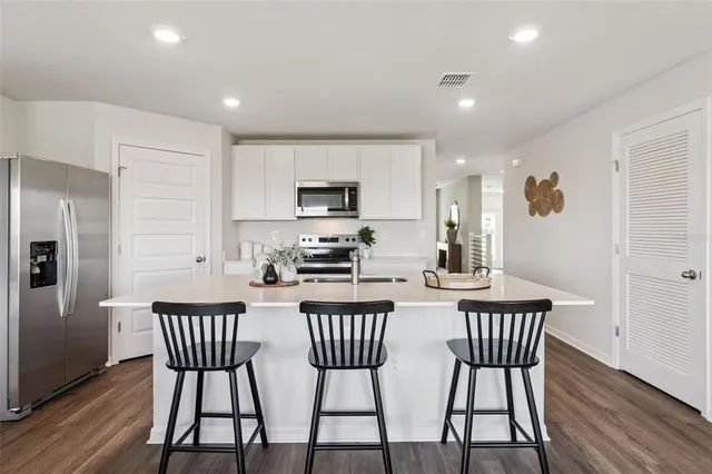 a kitchen with stainless steel appliances a dining table chairs and a refrigerator
