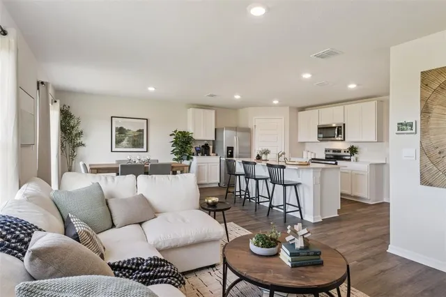 a living room with furniture kitchen and a wooden floor
