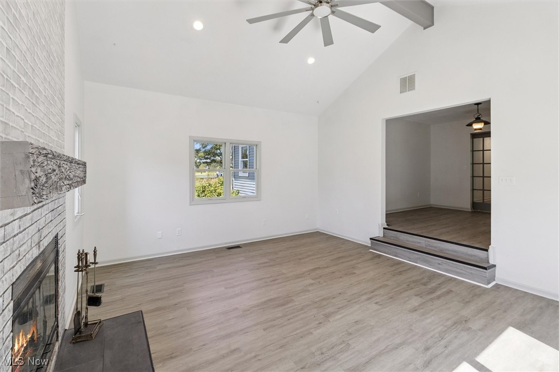 3930 Wood Road Madison, OH 44057 - Photo 15 of 45 Unfurnished living room with a fireplace, high vaulted ceiling, light wood-type flooring, recessed lighting, and beamed ceiling