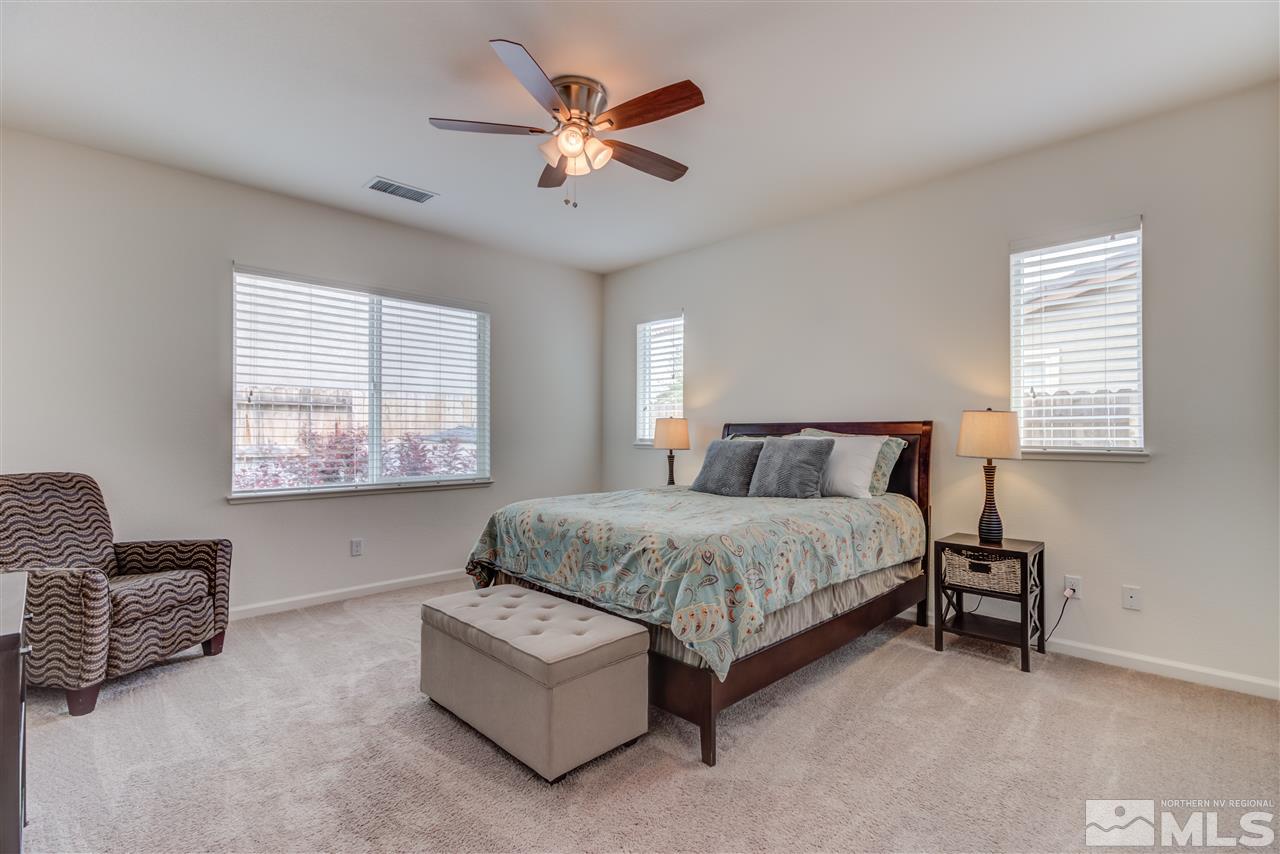 9340 Mill Iron Road Reno, NV 89521 - Photo 14 of 25 a spacious bedroom with a bed a couch and a window