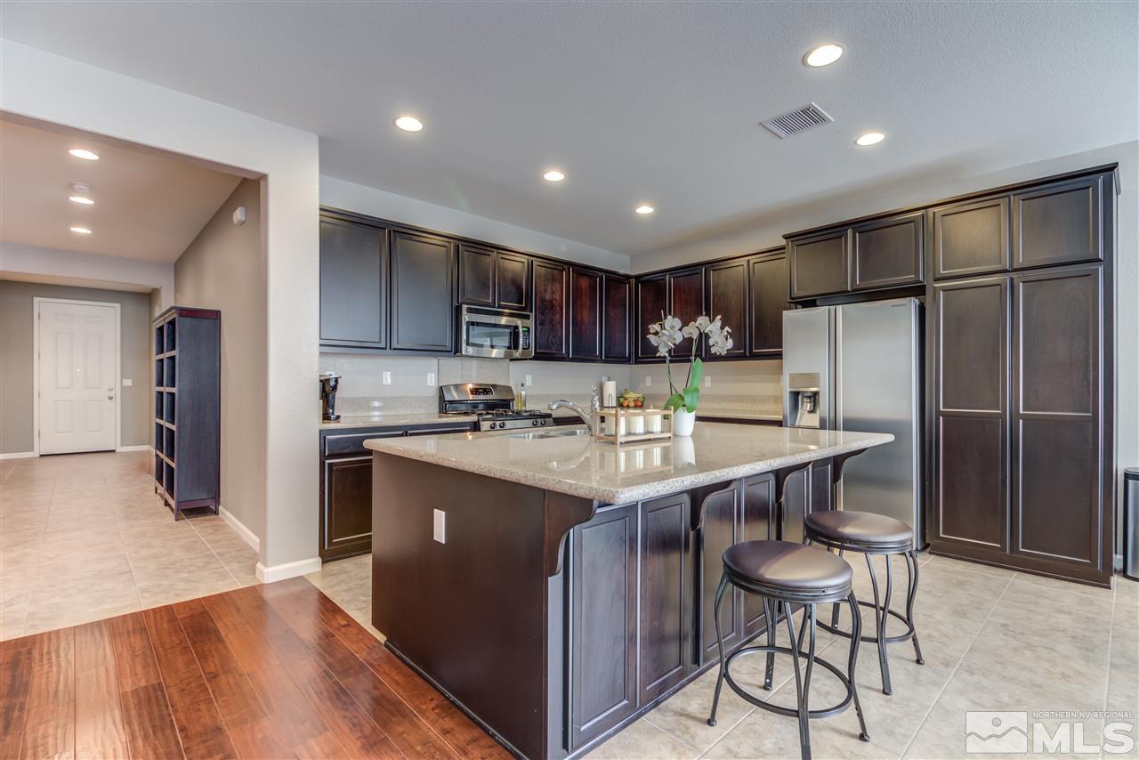 9340 Mill Iron Road Reno, NV 89521 - Photo 5 of 25 a kitchen with kitchen island granite countertop wooden cabinets a refrigerator and a stove top oven