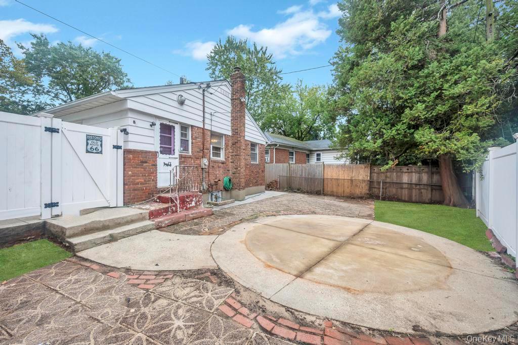 51 Stevenson Road Hewlett, NY 11557 - Photo 21 of 21 Rear view of house with a fenced backyard, a chimney, a gate, a patio area, and brick siding