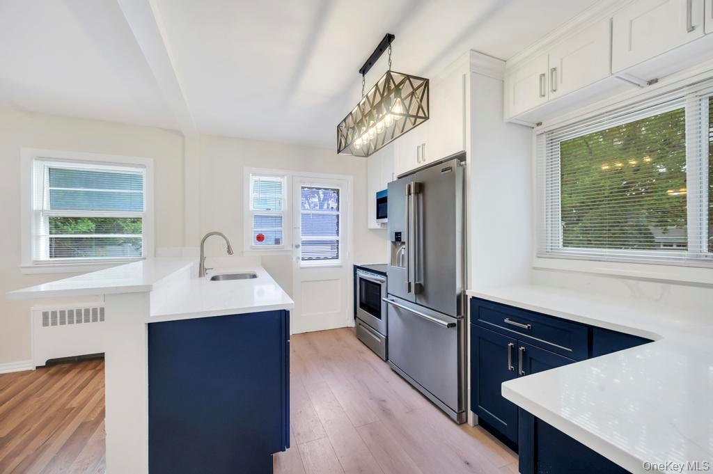 51 Stevenson Road Hewlett, NY 11557 - Photo 5 of 21 Kitchen featuring blue cabinets, white cabinetry, appliances with stainless steel finishes, and radiator heating unit