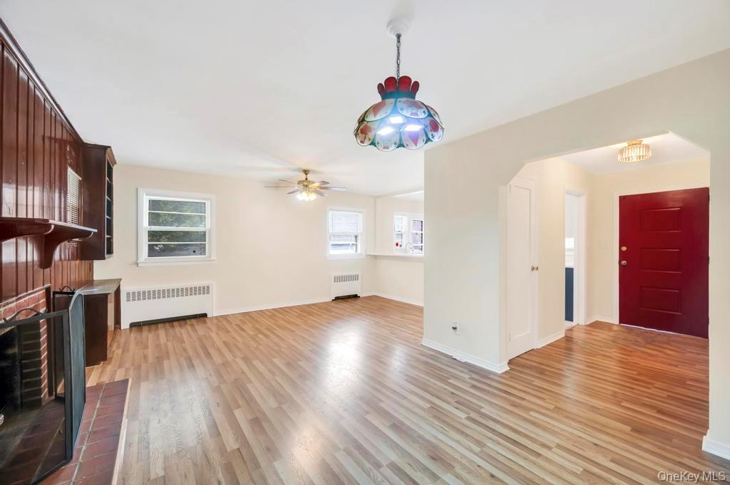 51 Stevenson Road Hewlett, NY 11557 - Photo 7 of 21 Unfurnished living room featuring radiator heating unit, light wood finished floors, arched walkways, and a fireplace
