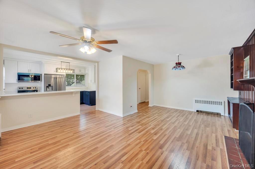 51 Stevenson Road Hewlett, NY 11557 - Photo 8 of 21 Unfurnished living room featuring light wood-style flooring, radiator heating unit, arched walkways, and a ceiling fan