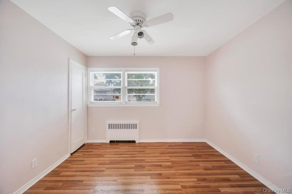51 Stevenson Road Hewlett, NY 11557 - Photo 10 of 21 Unfurnished room featuring radiator heating unit, wood finished floors, and a ceiling fan