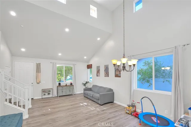 a view of kitchen with stainless steel appliances granite countertop wooden floor cabinets and a chandelier