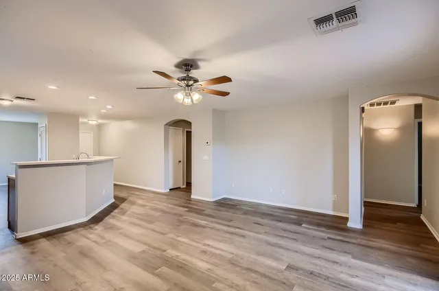 a view of an empty room with wooden floor and a ceiling fan
