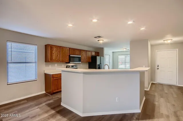 a living room with stainless steel appliances kitchen island a flat screen tv and a refrigerator