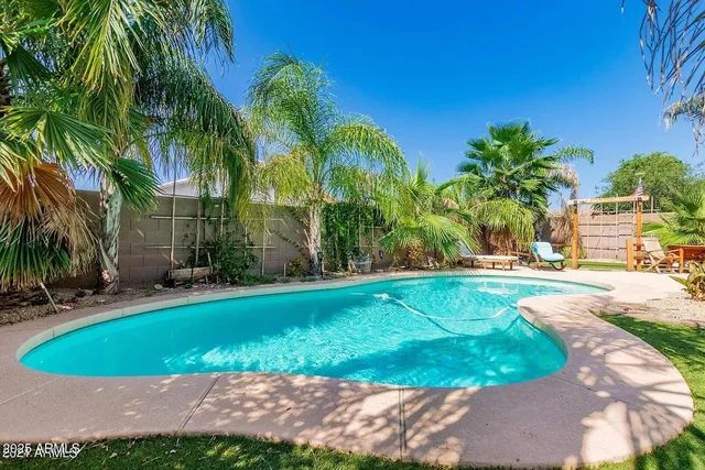 a view of a swimming pool with a yard and palm trees