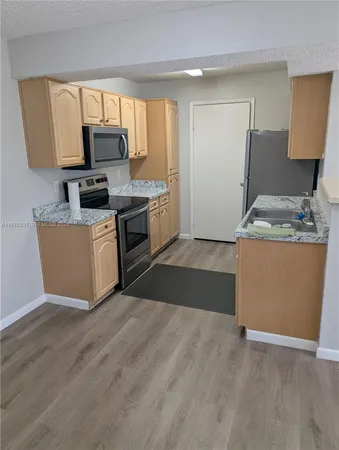 a kitchen with granite countertop a refrigerator and a stove top oven