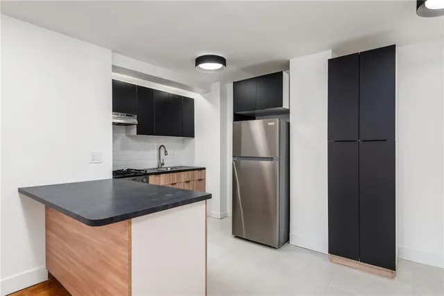 a kitchen with stainless steel appliances granite countertop a refrigerator a stove and a sink