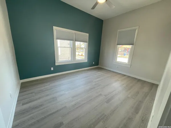 a view of an empty room with wooden floor and a window