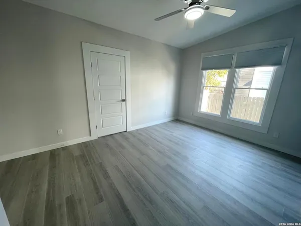 a view of an empty room with wooden floor and a window