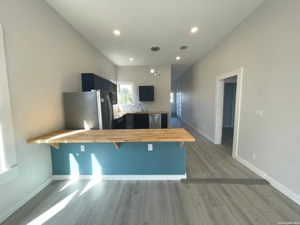 a view of a kitchen with kitchen island a sink wooden floor and a refrigerator
