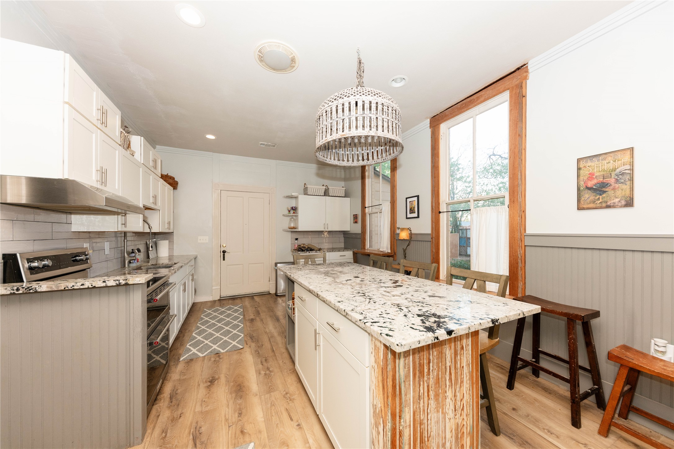 1202 Pecan Street Bastrop, TX 78602 - Photo 5 of 38 a kitchen with stainless steel appliances granite countertop a stove top oven a sink a dining table and chairs with wooden floor