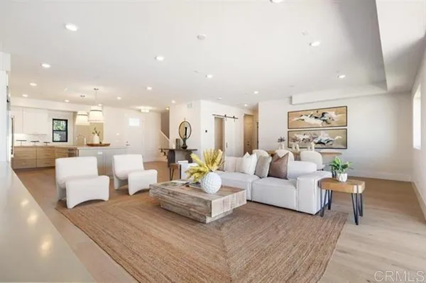 a living room with couches and a view of kitchen