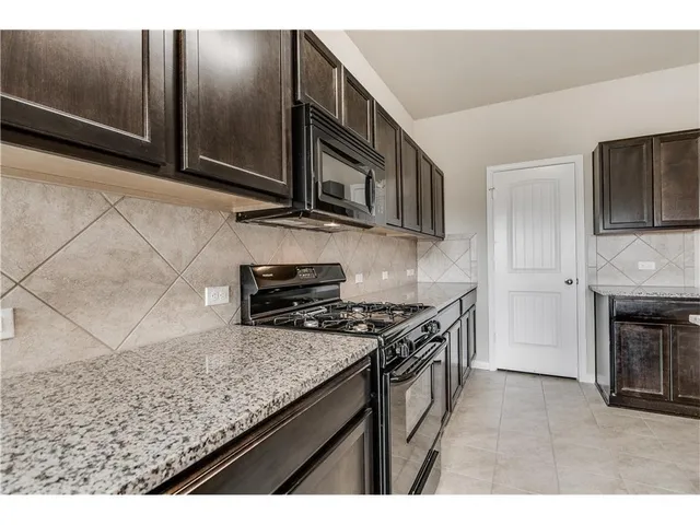 a kitchen with stainless steel appliances granite countertop a stove a sink and a microwave