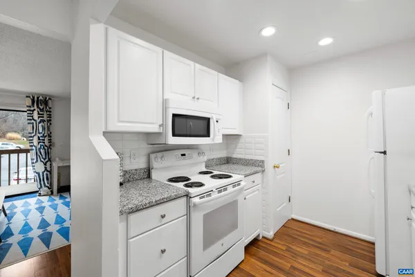 a kitchen with white cabinets and appliances