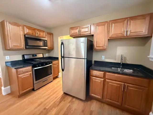 a kitchen with granite countertop wooden cabinets stainless steel appliances a sink and a window