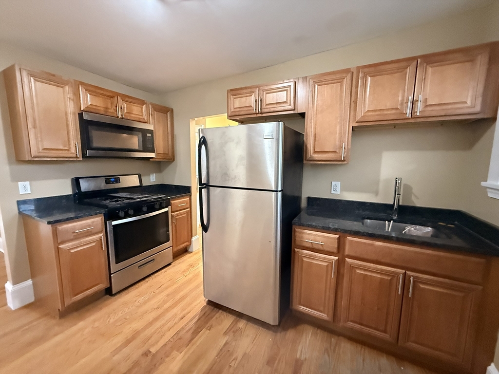 a kitchen with granite countertop wooden cabinets stainless steel appliances a sink and a window