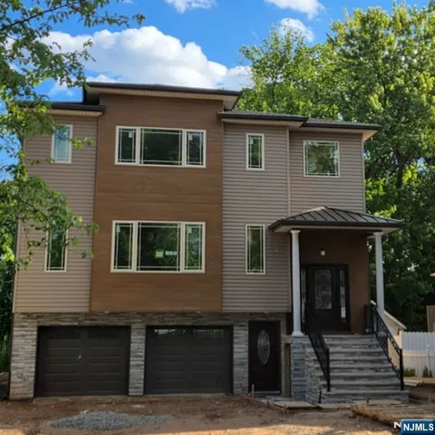 a kitchen with stainless steel appliances kitchen island granite countertop a stove a sink a refrigerator and white cabinets with wooden floor