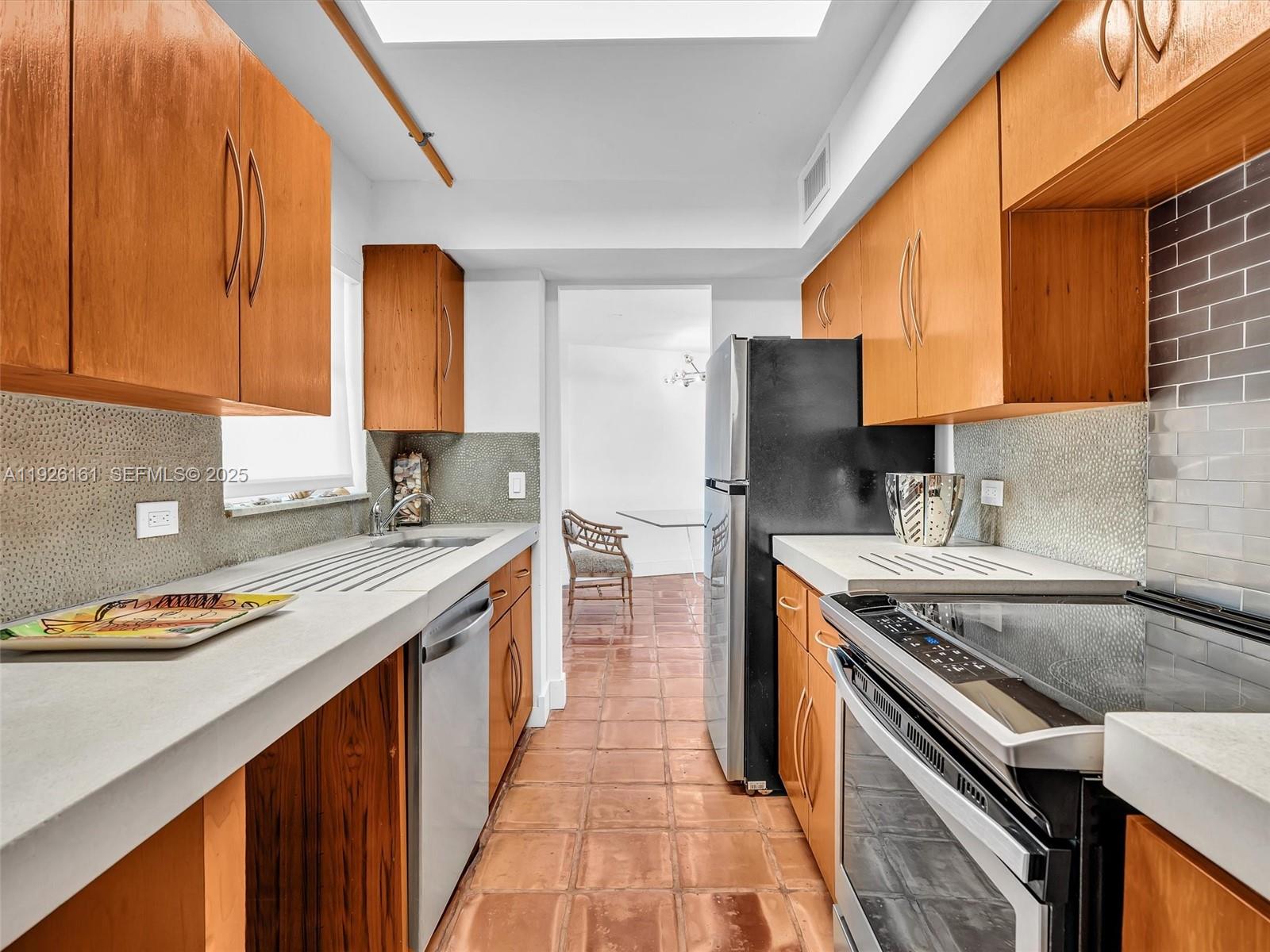 1881 Washington Avenue, Unit 16E Miami Beach, FL 33139 - Photo 12 of 65 a kitchen with stainless steel appliances granite countertop a sink stove and refrigerator