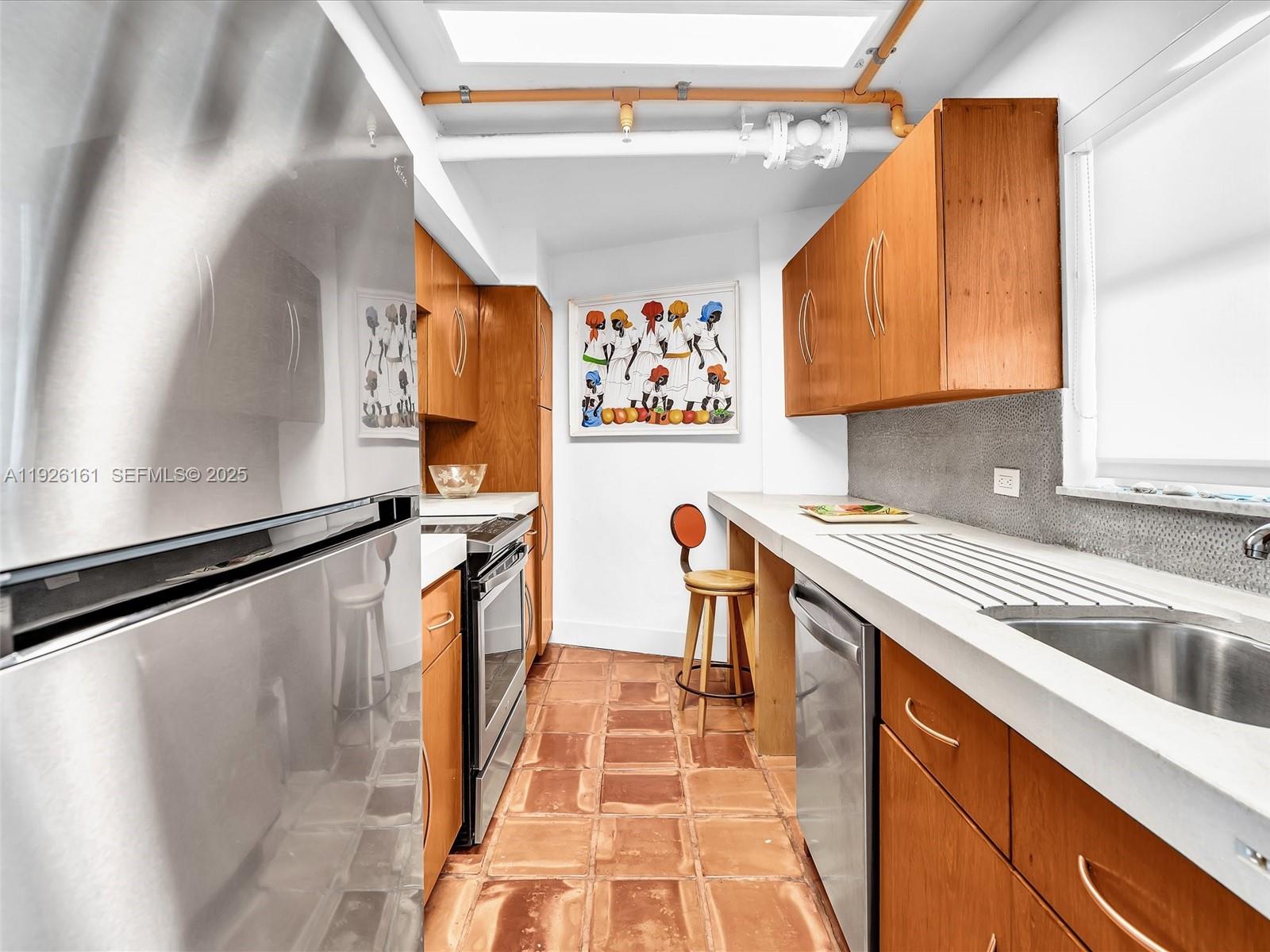 1881 Washington Avenue, Unit 16E Miami Beach, FL 33139 - Photo 4 of 65 a kitchen with a sink a refrigerator and cabinets
