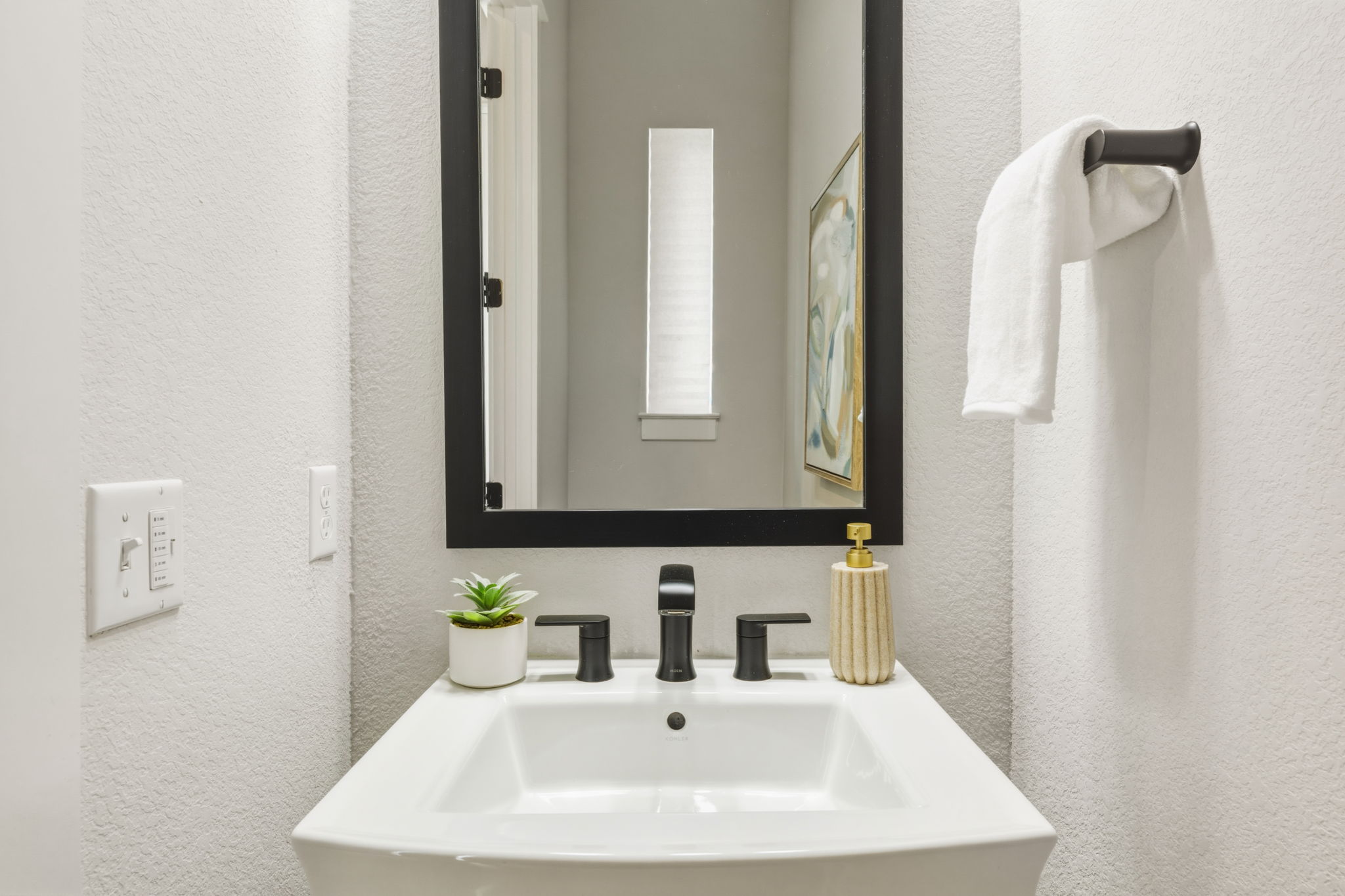 2929 Moreno Street Austin, TX 78723 - Photo 7 of 40 Pedestal sink with a matte black faucet, framed mirror, and a wall-mounted towel bar