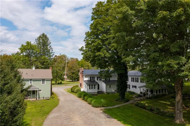 a view of a big house with a big yard and large trees