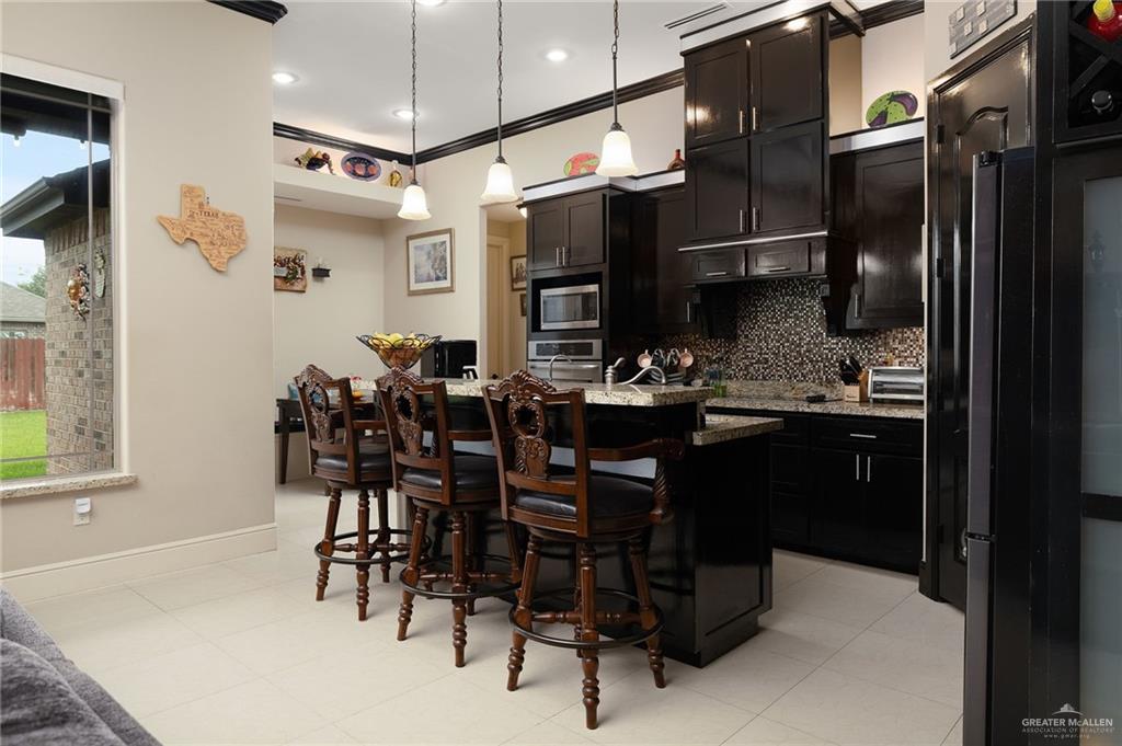 704 Santa Fe Street Weslaco, TX 78596 - Photo 11 of 25 a kitchen with stainless steel appliances kitchen island granite countertop a table chairs sink and cabinets
