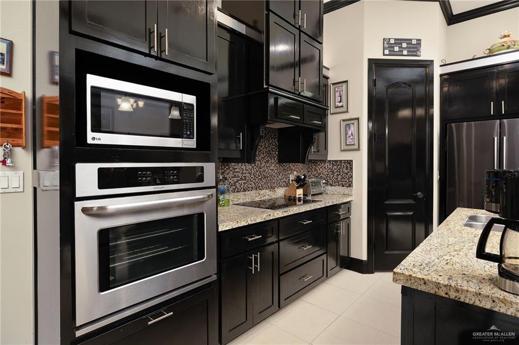 704 Santa Fe Street Weslaco, TX 78596 - Photo 12 of 25 a kitchen with stainless steel appliances kitchen island granite countertop a stove microwave and refrigerator