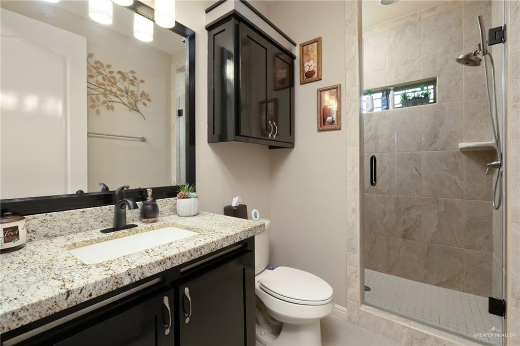 704 Santa Fe Street Weslaco, TX 78596 - Photo 17 of 25 a bathroom with a granite countertop sink a toilet and a mirror