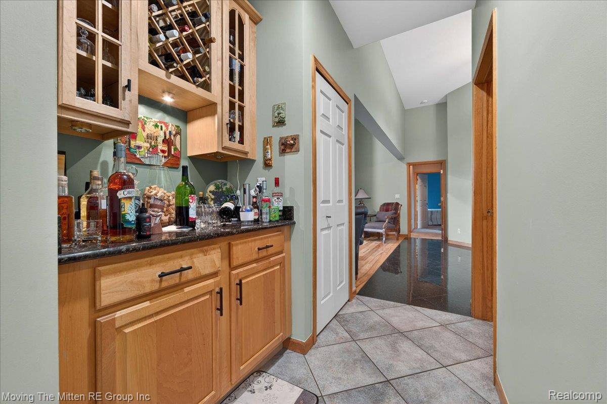 39750 Willow Road New Boston, MI 48164 - Photo 16 of 68 Custom built-in bar with wood-finish cabinetry, integrated wine rack, and a dark stone-finish countertop