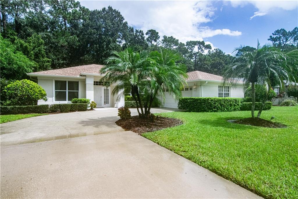 a view of a house with a yard and palm trees
