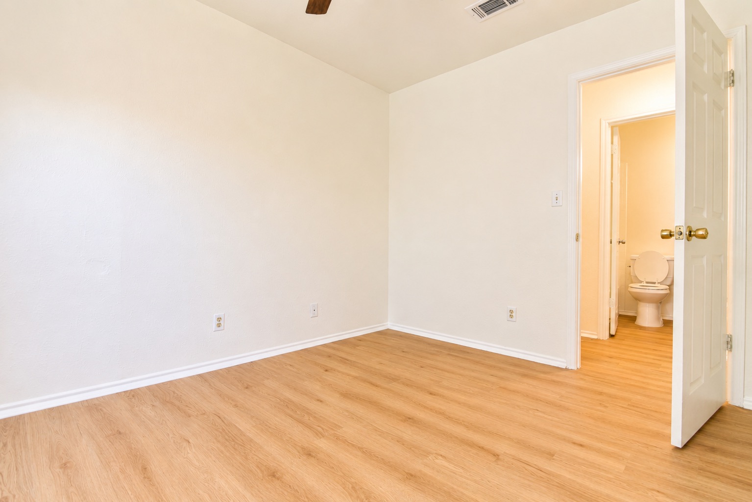 8807 Springmail Circle, Unit A Austin, TX 78729 - Photo 27 of 40 Laminate wood flooring extends into a bright room with a peek into an adjacent bath.