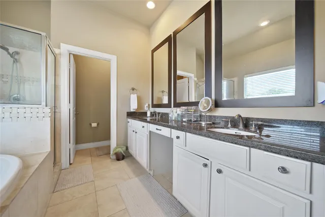 a bathroom with a double vanity sink a mirror and a bathtub