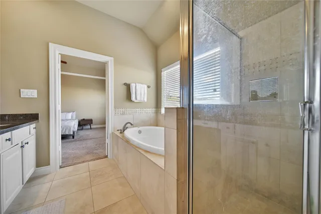 a en suite bathroom with a granite countertop tub a sink and a large mirror