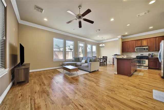a living room with stainless steel appliances furniture and a wooden floor