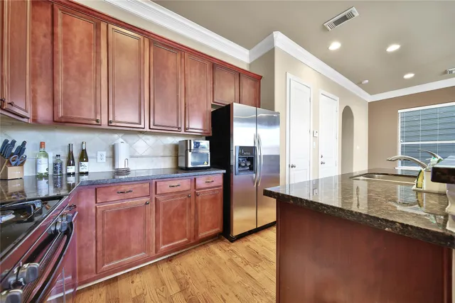 a kitchen with stainless steel appliances granite countertop a sink a stove and a refrigerator