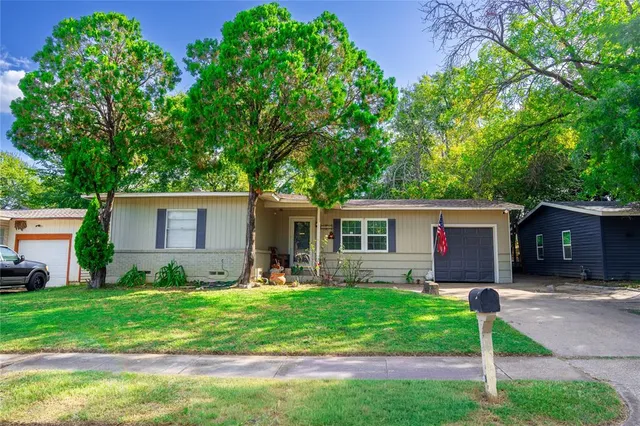 a backyard of a house with table and chairs plants and large tree