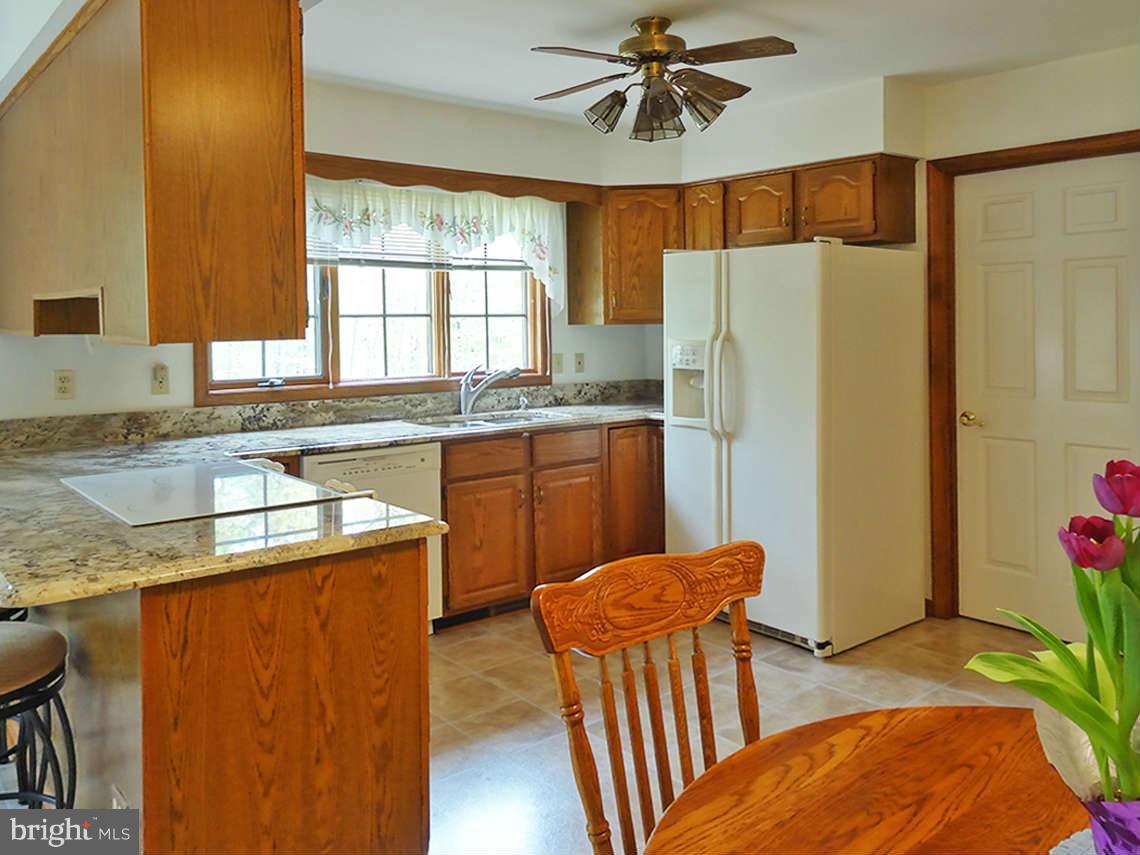 1200 Parran Road St. Leonard, MD 20685 - Photo 26 of 29 a kitchen with stainless steel appliances granite countertop a refrigerator a sink dishwasher a dining table and chairs with wooden floor