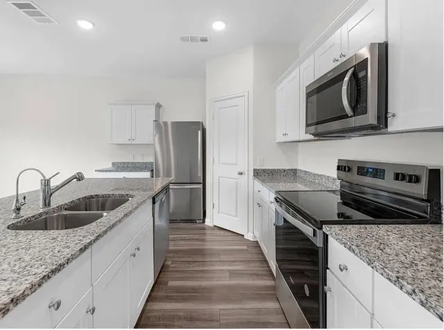 a kitchen with stainless steel appliances granite countertop a sink stove and refrigerator