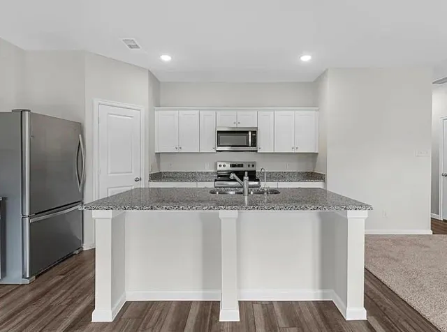 a kitchen with stainless steel appliances granite countertop a refrigerator a stove a sink and a microwave